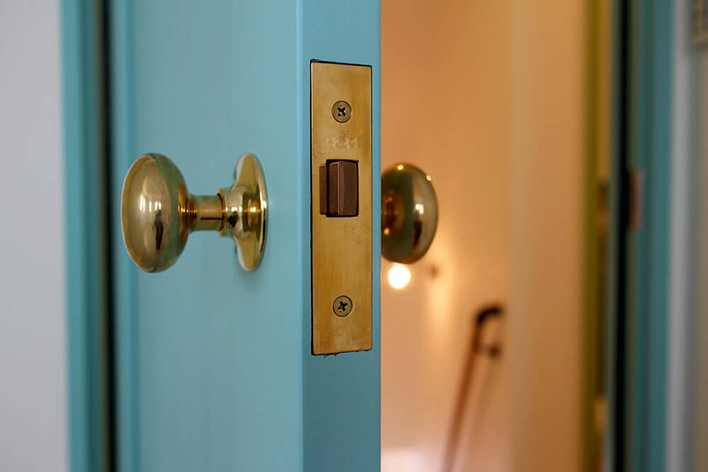 パステルカラーがかわいい、淡いブルーの室内ドアと真鍮ノブ